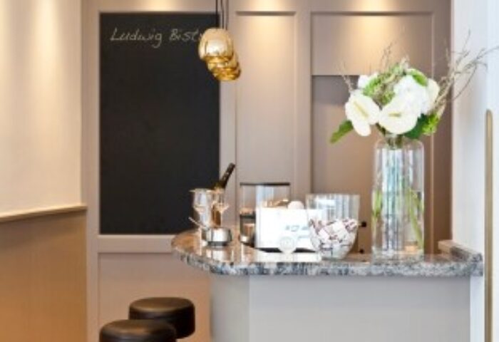 Hotel Beethoven Wien's gay-friendly bistro. Bar with stools, blackboard, champagne, and flowers. A welcoming space for LGBT travelers.