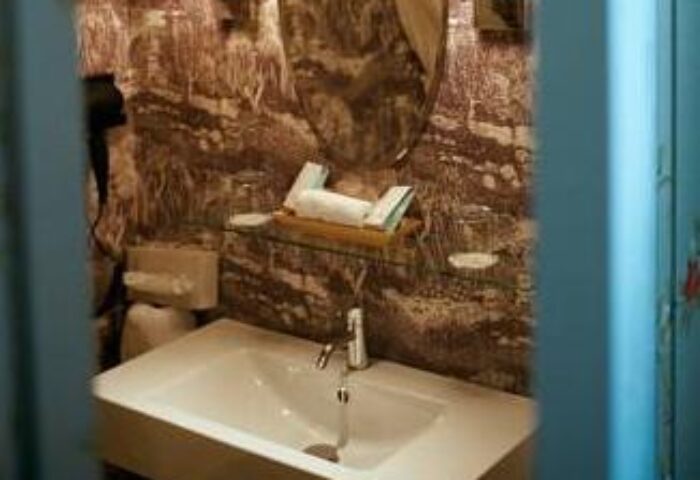 Bathroom in Hotel Beethoven Wien, a gay-friendly hotel. Sink, toilet, and patterned wallpaper. Ideal for gay men's travel in Vienna.