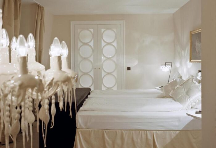 Hotel Beethoven Wien room. A gay-friendly hotel with a bed, chandelier, and white decor. Ideal for gay men's travel in Vienna.