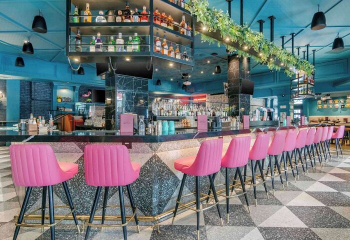 Hotel Belmont Vancouver Mgallery's bar area. Gay-friendly hotel with pink bar stools, a fully stocked bar, and a stylish black and white floor.