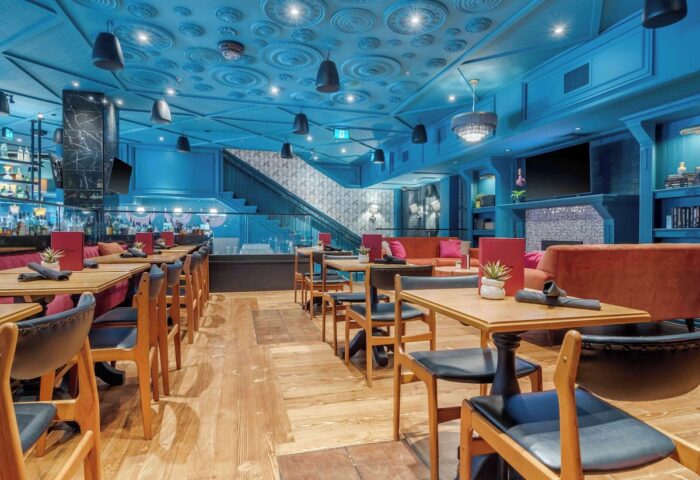 Hotel Belmont Vancouver Mgallery's gay-friendly dining area. Tables, chairs, and a staircase are visible in this stylish hotel.