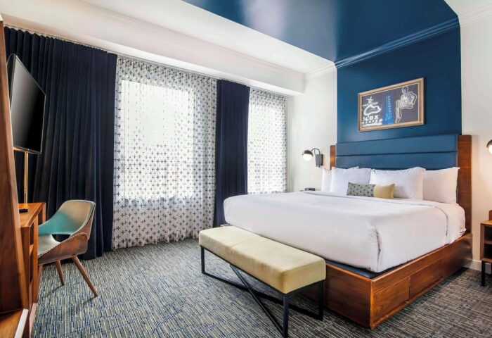 Hotel Belmont Vancouver Mgallery room. Gay-friendly hotel with a king bed, blue accents, desk, and bench. Modern design.