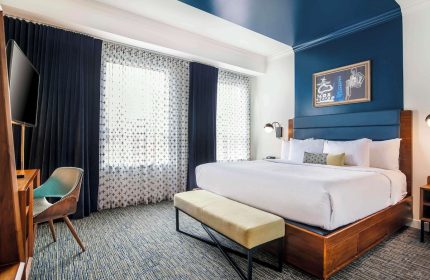 Hotel Belmont Vancouver Mgallery room. Gay-friendly hotel with a king bed, blue accents, desk, and bench. Modern design.