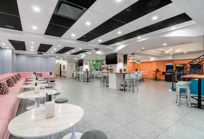 Hotel Belmont Vancouver Mgallery's stylish interior. Gay-friendly hotel with bar stools, pink booths, arcade games, and modern design. A vibrant space.