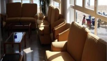 Hotel Bilbaino's gay-friendly lounge area with sofas and chairs. Beach view through the window. Ideal for gay men's travel in Bilbao.
