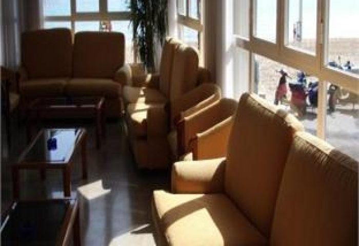 Hotel Bilbaino's gay-friendly lounge area with sofas and chairs. Beach view through the window. Ideal for gay men's travel in Bilbao.