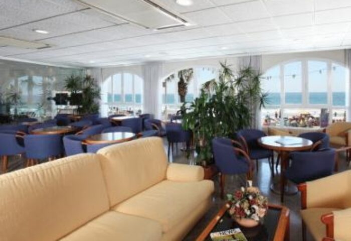 Hotel Bilbaino's lounge area. Gay-friendly hotel interior with sofas, chairs, tables, and ocean views. A relaxing space for gay travelers.