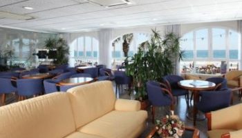 Hotel Bilbaino's lounge area. Gay-friendly hotel interior with sofas, chairs, tables, and ocean views. A relaxing space for gay travelers.