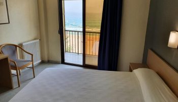 Hotel Bilbaino room with sea view. Gay-friendly hotel featuring a bed, chair, and balcony overlooking the beach. Perfect for gay travel.