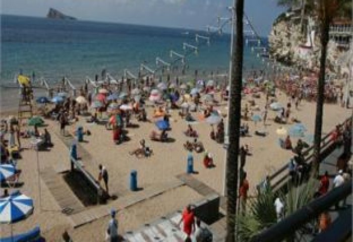 Hotel Bilbaino, a gay-friendly hotel: Crowded beach scene with sunbathers, umbrellas, and palm trees. Ideal for gay travel.