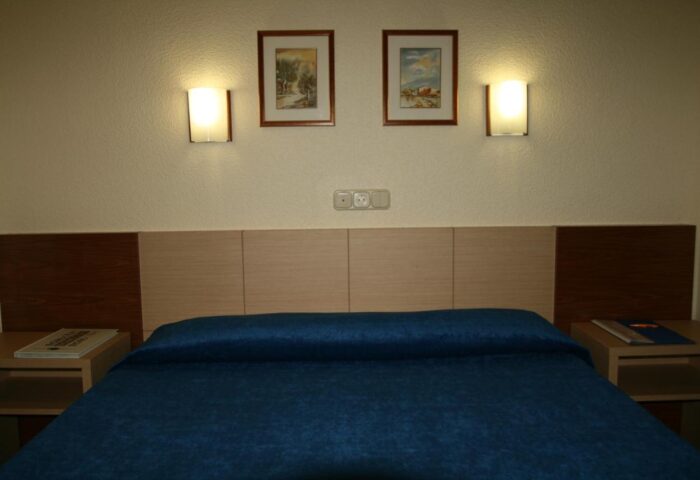 Hotel Bilbaino gay-friendly room. Blue bedspread, wooden headboard, bedside tables, and wall art. A comfortable stay for gay travelers.