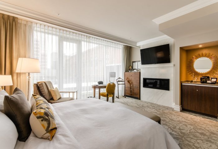 Hotel Birks Montreal's gay-friendly room. Luxurious bedroom with a large bed, fireplace, TV, desk, and city view. Upscale travel for gay men.