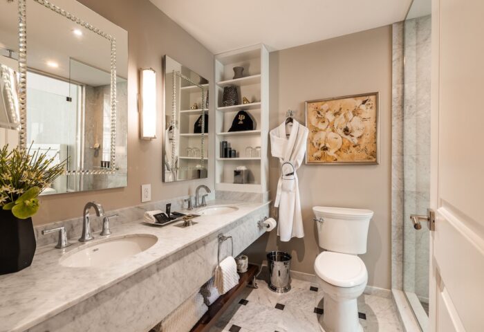 Bathroom at Hotel Birks Montreal, a gay-friendly hotel. Marble counters, dual sinks, and a robe. Upscale design for gay travelers.