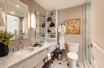 Bathroom at Hotel Birks Montreal, a gay-friendly hotel. Marble counters, dual sinks, and a robe. Upscale design for gay travelers.