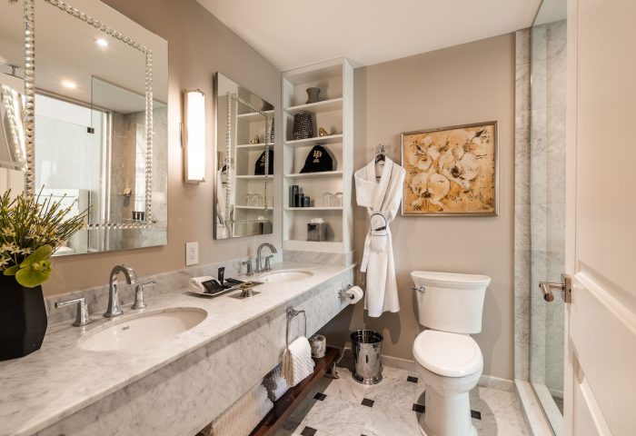 Bathroom at Hotel Birks Montreal, a gay-friendly hotel. Marble counters, dual sinks, and a robe. Upscale design for gay travelers.