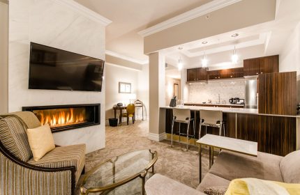 Hotel Birks Montreal suite interior. Gay-friendly hotel room with fireplace, TV, kitchen, seating area. Luxury travel and accommodation.
