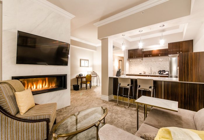 Hotel Birks Montreal suite interior. Gay-friendly hotel room with fireplace, TV, kitchen, seating area. Luxury travel and accommodation.