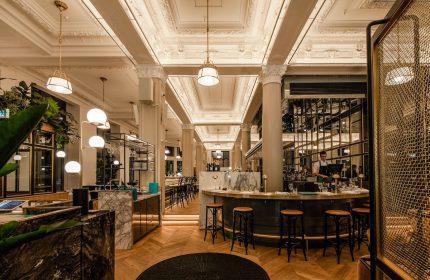 Hotel Birks Montreal's gay-friendly bar area. Elegant interior with marble counters, stylish lighting, and herringbone wood floors.