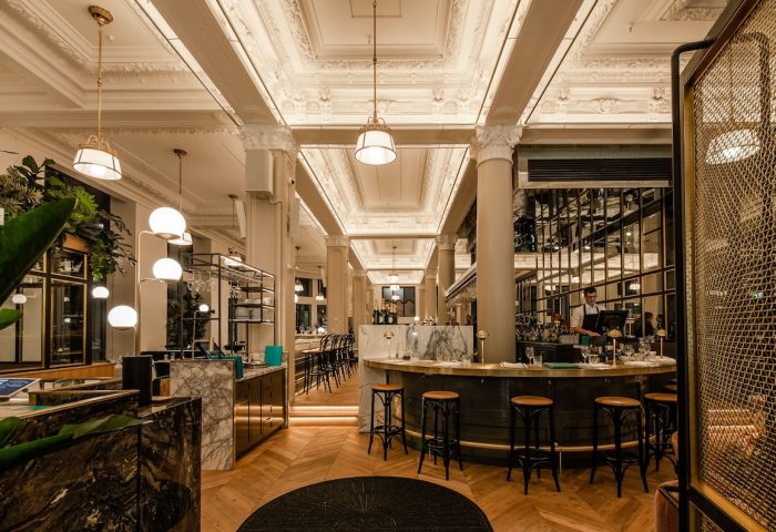 Hotel Birks Montreal's gay-friendly bar area. Elegant interior with marble counters, stylish lighting, and herringbone wood floors.