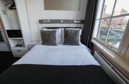 Hotel CC gay-friendly hotel room interior. Double bed with gray pillows, safe, and canal view. Modern design for gay men travelers.