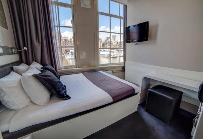 Hotel CC Gay-Friendly Hotel room. Bed with pillows, desk, stool, and TV. Canal view from window. Amsterdam gay travel lodging.