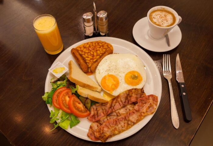 Hotel CC gay-friendly hotel breakfast: fried eggs, bacon, beans, toast, salad, orange juice, and coffee. A delicious start to your gay travel day.