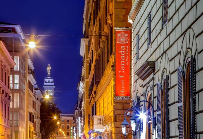 Gay-Friendly Hotel Canada at night. Street view of the hotel's sign. Statue visible in the distance. Rome gay travel advice.