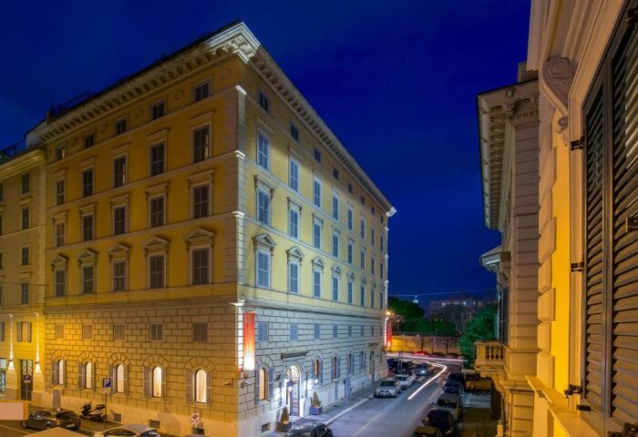 Hotel Canada, a gay-friendly hotel in Rome. Exterior view at night showing the building's architecture and street with cars.