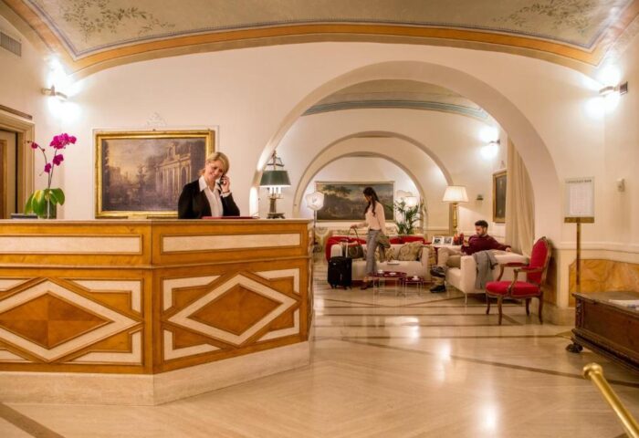 Hotel Canada's lobby. Gay-friendly hotel reception with staff on phone. Guests relaxing in lounge area. Elegant, welcoming atmosphere.