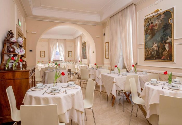 Hotel Canada's dining room. Gay-friendly hotel with tables set for breakfast, white linens, tulips, and antique art. Elegant and inviting space.