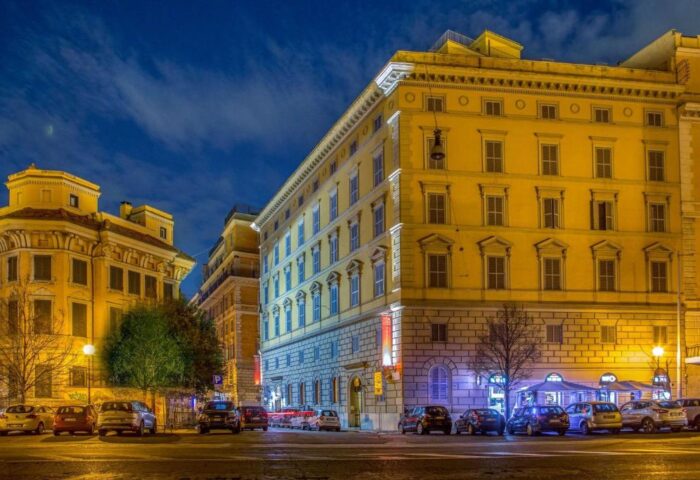 Hotel Canada, a gay-friendly hotel, at night. Yellow buildings with parked cars. Travel advice for gay men.