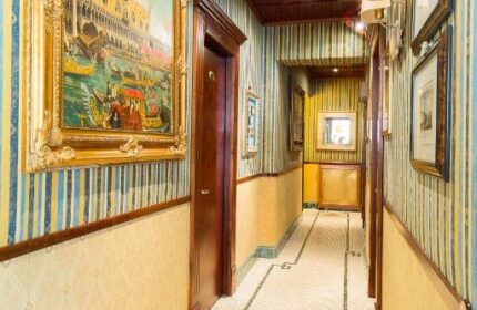 Hallway view at Hotel Celio, a gay-friendly hotel. Striped wallpaper, tiled floor, and framed art. A charming and stylish stay for gay travelers.