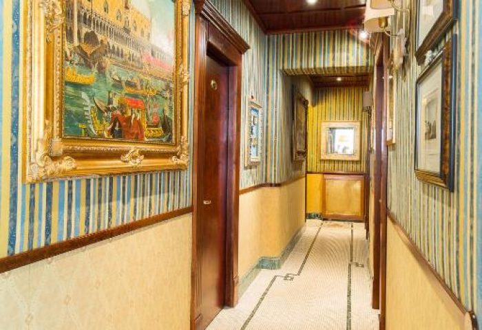 Hallway view at Hotel Celio, a gay-friendly hotel. Striped wallpaper, tiled floor, and framed art. A charming and stylish stay for gay travelers.