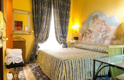 Hotel Celio gay-friendly hotel room. A double bed with a painted headboard, blue floral carpet, and yellow walls. Gay travel in Rome.