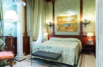 Hotel Celio gay-friendly hotel room. Luxurious suite with columns, patterned wallpaper, and mosaic tile floor. Comfortable gay travel.