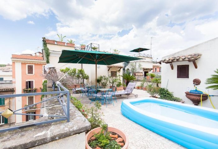 Hotel Celio: Gay-Friendly Hotel rooftop terrace view. Outdoor seating, umbrella, inflatable pool and city views for gay men travelers in Rome.