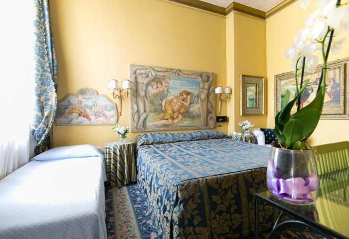 Hotel Celio gay-friendly room. Double bed with blue patterned cover, art above. Gay travel in Rome, Italy. Comfortable, welcoming hotel.