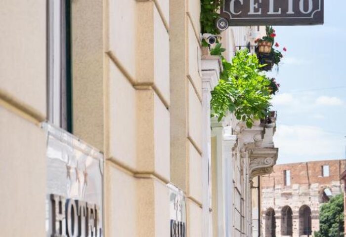 Hotel Celio, a gay-friendly hotel in Rome. Building exterior with the hotel's sign. The Colosseum is visible in the background. Travel advice.