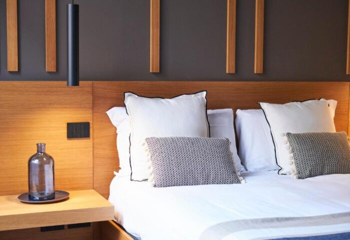 Hotel Central Lodge room detail. Gay-friendly hotel bedroom with pillows, wooden headboard, bedside table, and modern design. Perfect for gay travel.