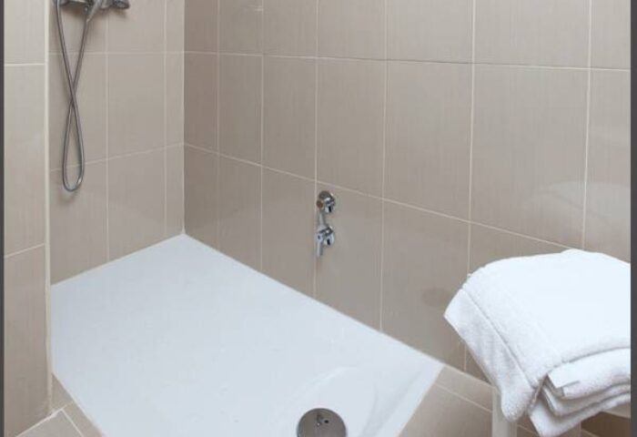 Hotel Centro Mar gay-friendly shower. Walk-in shower with neutral tile, shower head, and towels. Ideal for gay men's travel in a welcoming hotel.