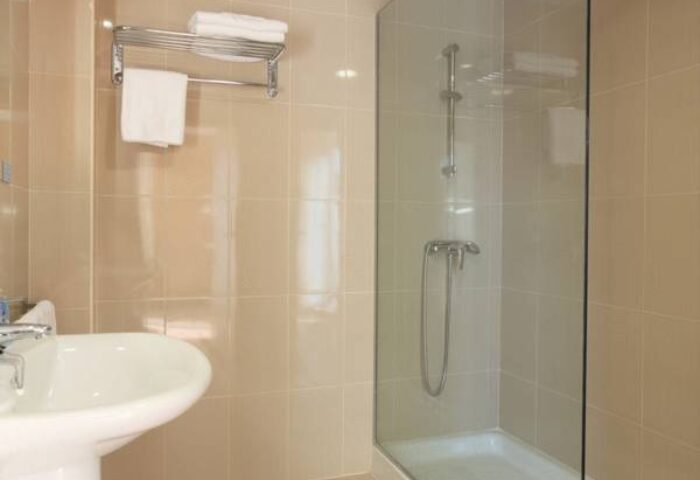 Bathroom at Hotel Centro Mar, a gay-friendly hotel. Features a sink, shower with glass door, and towel rack. Clean and modern design.