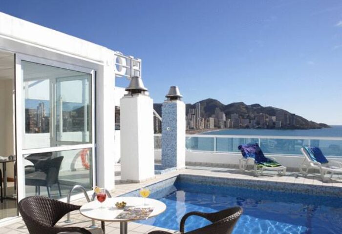 Hotel Centro Mar, a gay-friendly hotel. Rooftop pool with ocean view, chairs, and table with drinks. Ideal for gay travel advice.