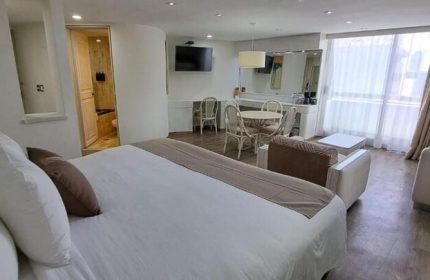 Hotel Century Reforma gay-friendly room. Modern interior with bed, seating area, TV, and dining table. Comfortable and stylish accommodations.