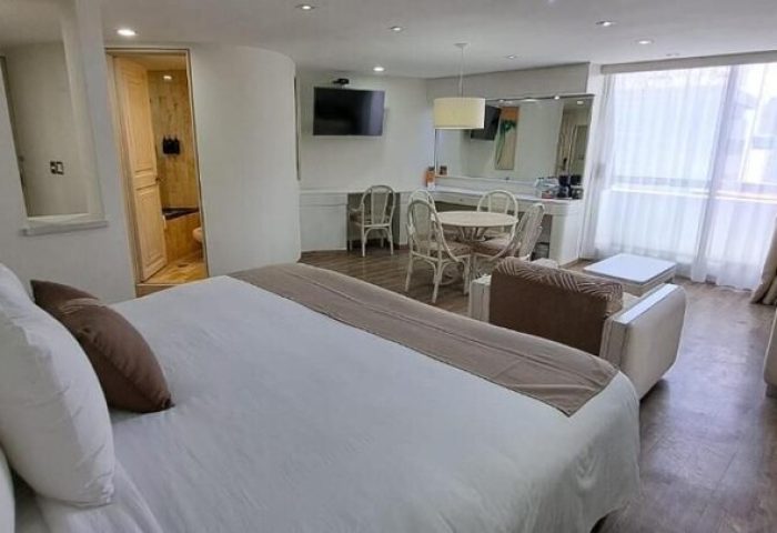 Hotel Century Reforma gay-friendly room. Modern interior with bed, seating area, TV, and dining table. Comfortable and stylish accommodations.
