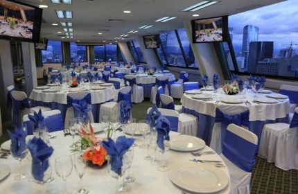 Gay-friendly Hotel Century Reforma banquet room. Tables set with white linens and blue accents, cityscape view. Ideal for events.