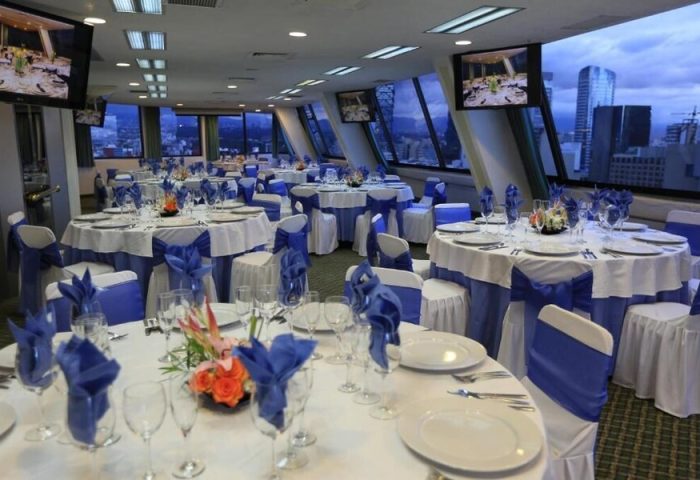 Gay-friendly Hotel Century Reforma banquet room. Tables set with white linens and blue accents, cityscape view. Ideal for events.