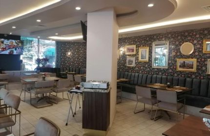Hotel Century Reforma's gay-friendly dining area. Tables and chairs sit on a tiled floor. Floral wallpaper and framed art decorate the walls.