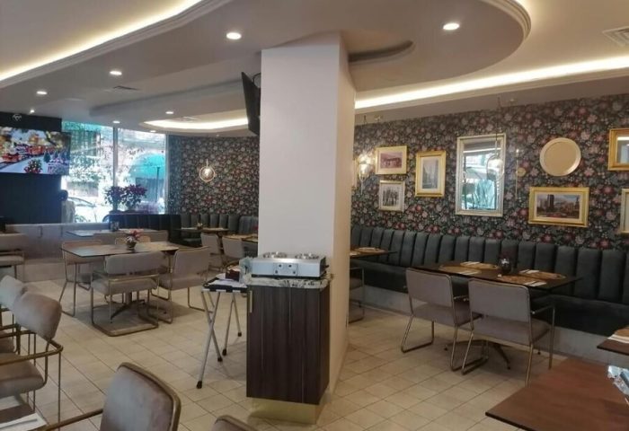 Hotel Century Reforma's gay-friendly dining area. Tables and chairs sit on a tiled floor. Floral wallpaper and framed art decorate the walls.