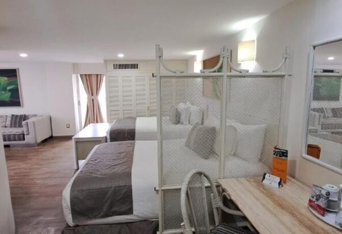 Hotel Century Reforma gay-friendly hotel room. Two beds with a divider, desk, and seating area. Modern decor for gay men travelers.