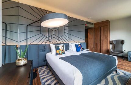 Hotel Clark Budapest: A pet-friendly, gay-friendly hotel room with a bed, pillows, geometric wall design, and modern lighting.